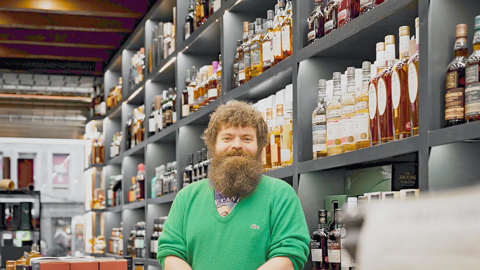 Smiling shop owner standing in front of his shelves