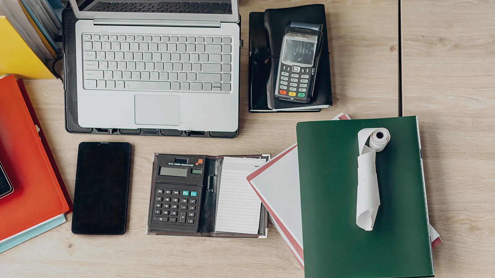 Laptop, card reader and ledger on an owner's desk