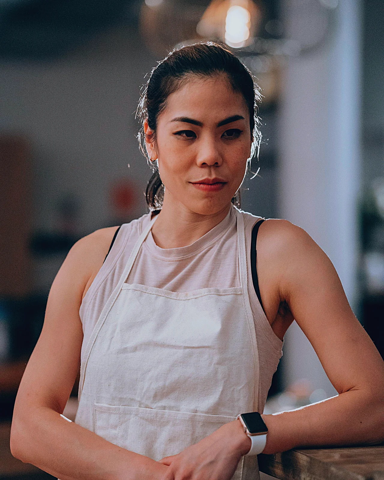 Cafe owner in an apron leaning on her counter
