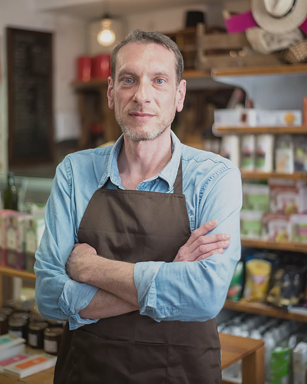 Shop owner in an apron with arms crossed in his store